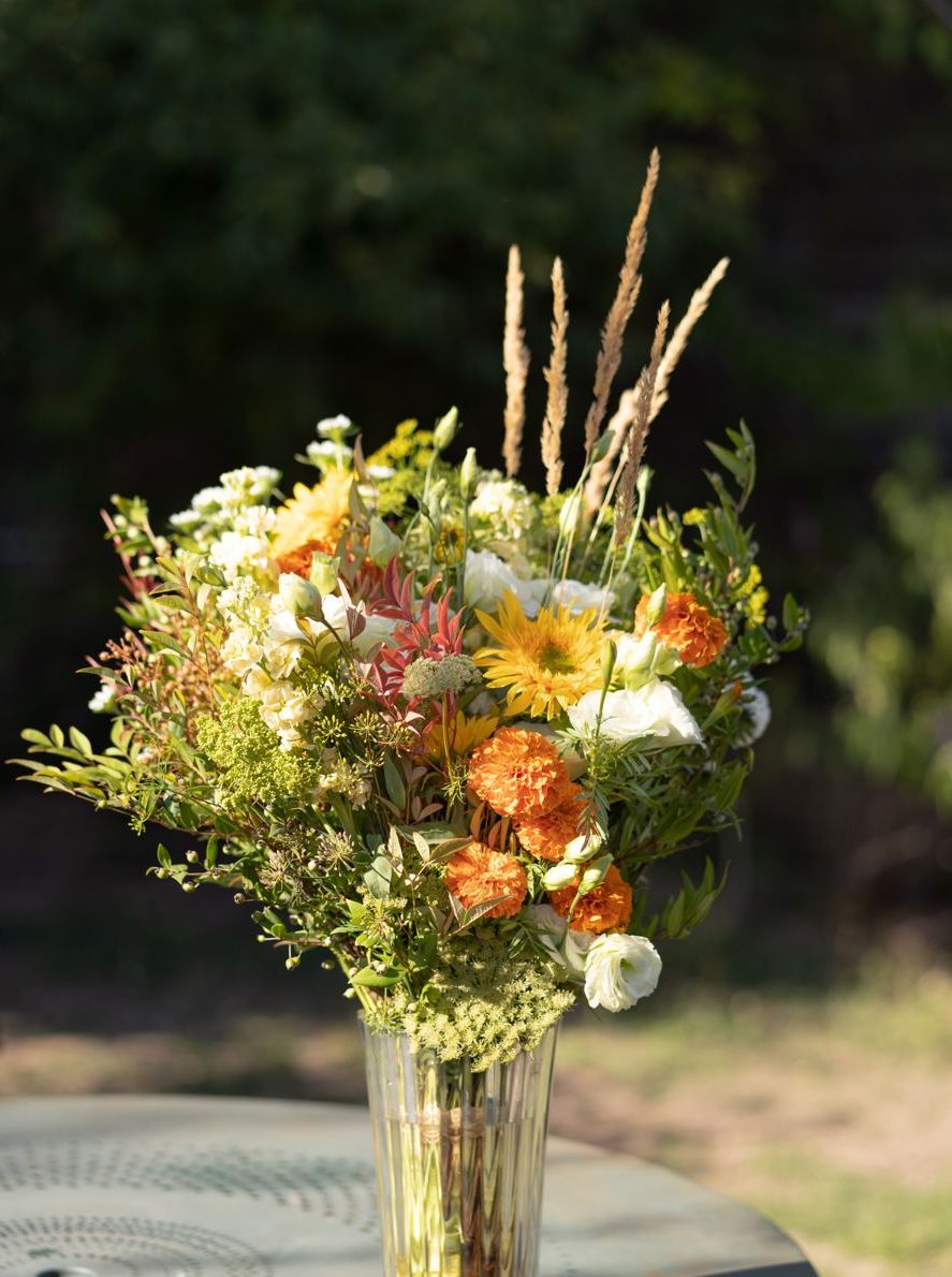 Grand bouquet aux tons chauds sur une table de jardin